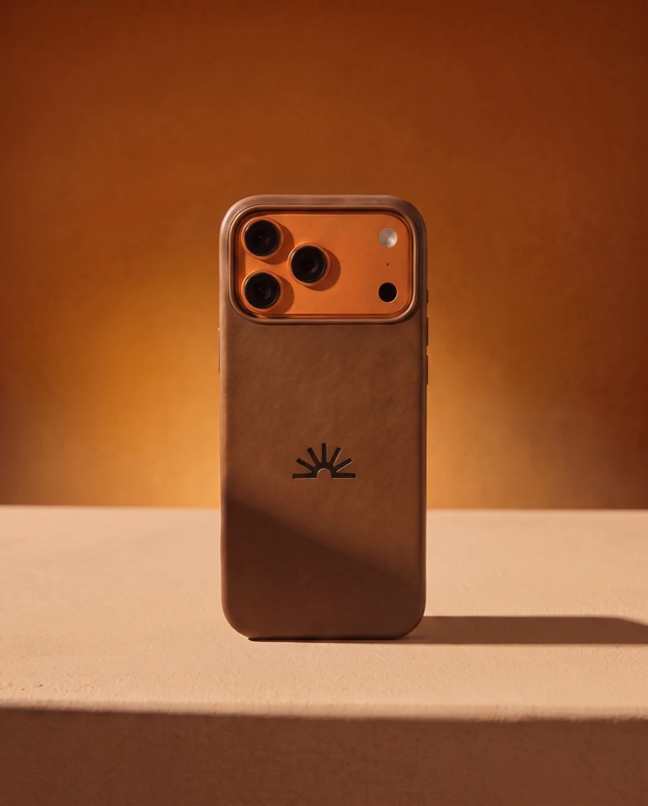 Brown phone case with an orange camera ring and sun logo