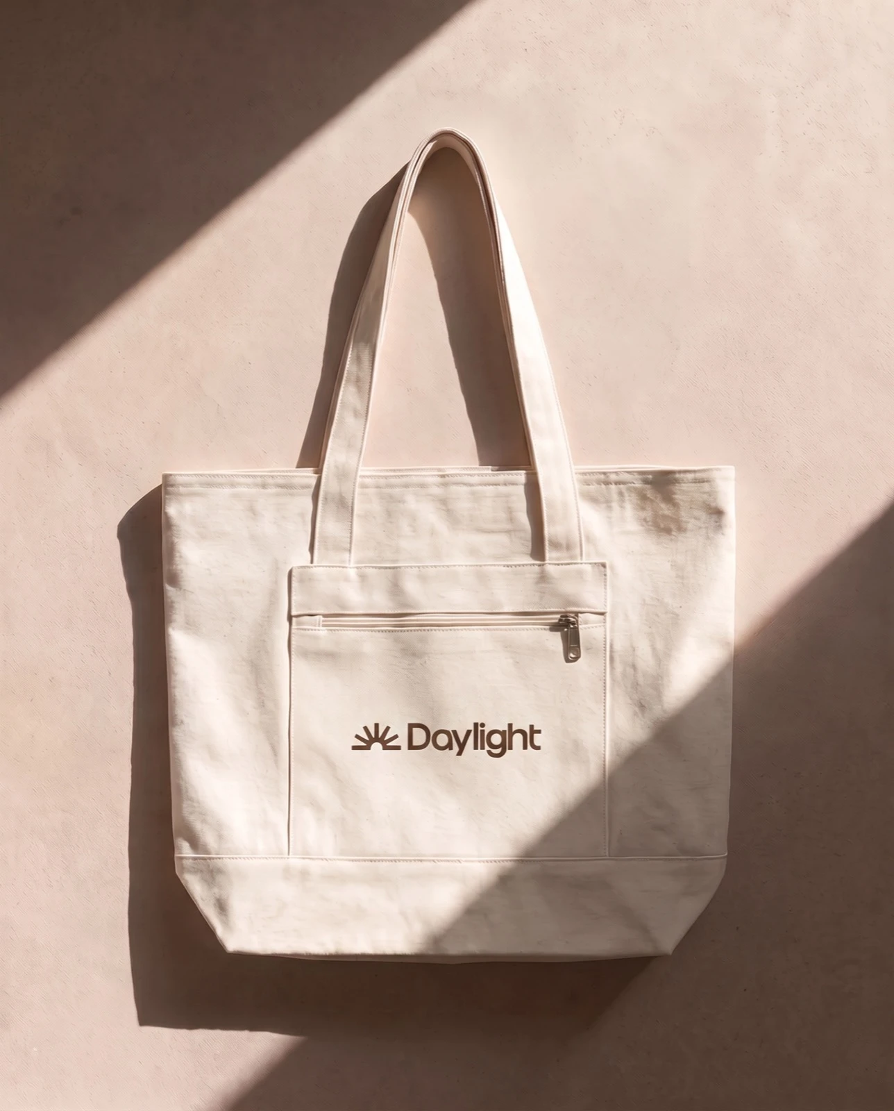 Cream canvas tote with the Daylight logo against a beige wall