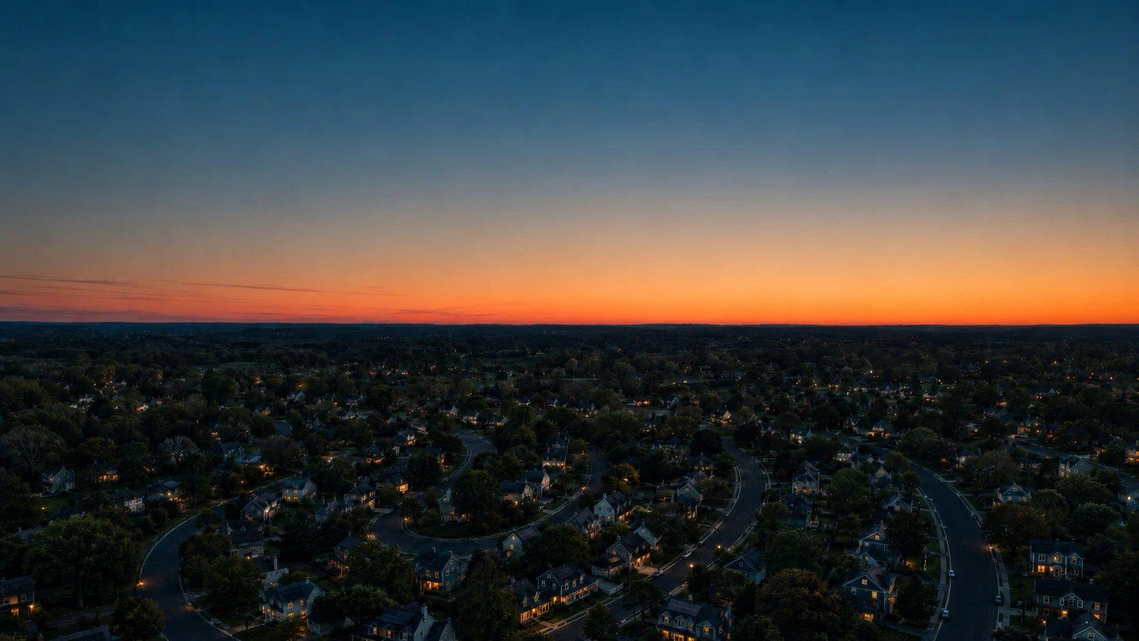 Aerial view of a suburban town under an orange twilight sky